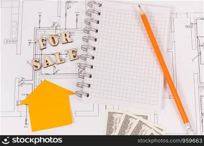 Inscription for sale, notepad with pencil for writing notes and money on electrical drawing, selling and buying house or flat concept. Inscription for sale, notepad with pencil and money on electrical drawing, selling and buying house or flat concept