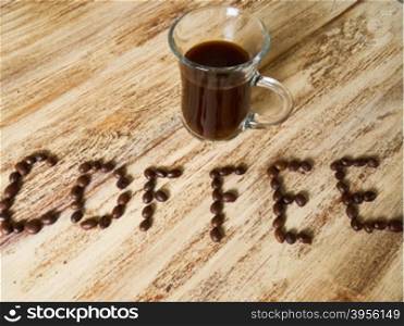inscription from coffee beans and coffee Cup on wooden background. inscription from coffee beans