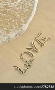 "Inscription "love" on sand. Sea coast with a rolling wave on an inscription"