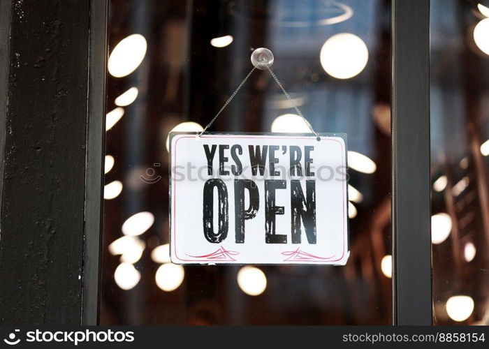 Inscription Yes we’re open metal plate with black and white sign on glass door store, cafe, beautystore, barbershop after coronavirus lockdown quarantine. business reopen again.. Inscription Yes we’re open metal plate with black and white sign on glass door store, cafe, beautystore, barbershop after coronavirus lockdown quarantine. business reopen again