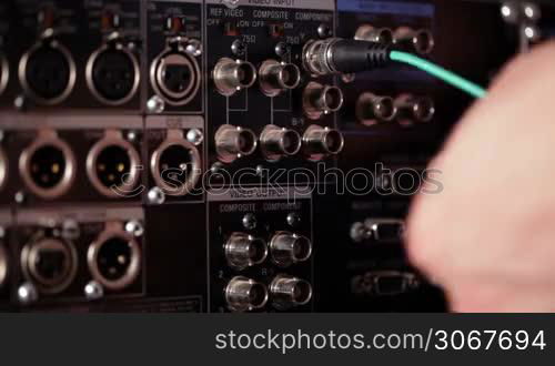 Inserting RGB video cables and XLR sound cables to the rear panel of the professional VCR. Time lapse.