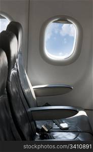 Inside an empty plane. Window and blue cloudy sky