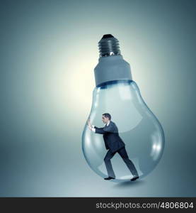 Inside light bulb. Businessman inside light bulb trying to get out