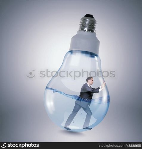 Inside light bulb. Businessman inside light bulb trying to get out