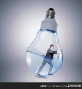 Inside light bulb. Businessman inside light bulb trying to get out