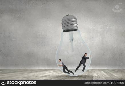 Inside light bulb. Businesswoman and businessman inside light bulb trying to get out