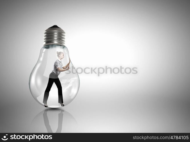 Inside light bulb. Businesswoman inside light bulb trying to get out