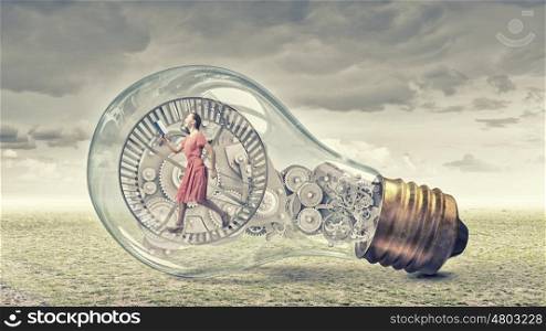 Inside light bulb. Young woman in dress with book in hands inside glass light bulb