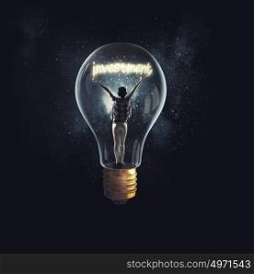 Inside of bright idea. Cheerful girl inside of glass light bulb on dark background