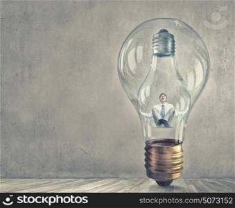 Inside of idea. Young businessman trapped inside of light bulb and calling for help