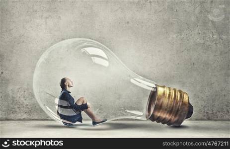 Inside of idea. Young woman sitting inside of glass light bulb