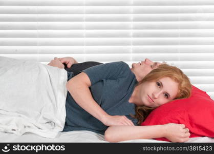 Insomniac woman laying next to sleeping man