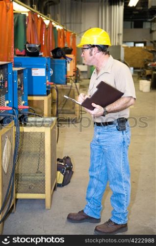 Inspector performing a safety Check of welding equipment in a metal work factory.
