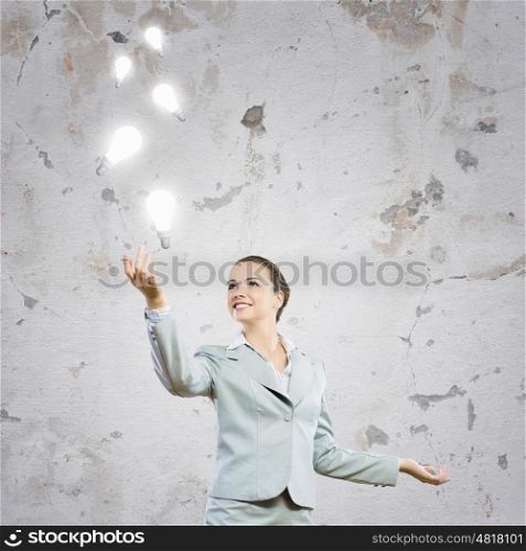 Inspiration. Image of attractive smiling businesswoman holding light bulbs on hand