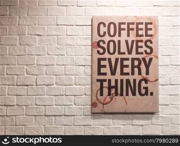 Inspirational motivating quote about coffee on canvas frame hanging on brick wall in the cafe&#xD;