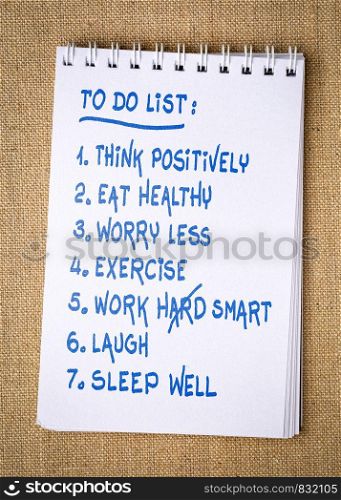 inspiring and positive to do list - handwriting in a spiral sketchbook against burlap canvas background