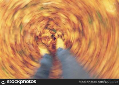 Instagram filter motion blurred photograph of man or womans feet walking through golden Fall or Autumn leaves