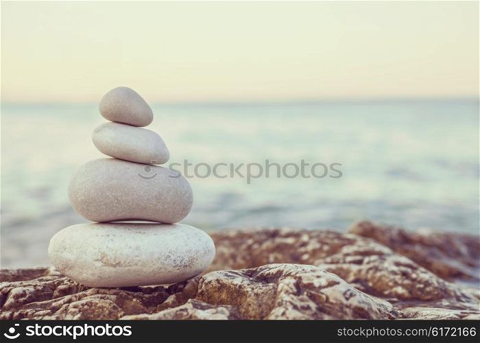 Instagram filter style tower of stones piles on top of a rock on a tranquil deserted beach at evening sunset