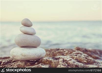 Instagram filter style tower of stones piles on top of a rock on a tranquil deserted beach at evening sunset