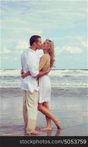 Instagram style photograph of romantic young man and woman couple embracing and kissing on a beach