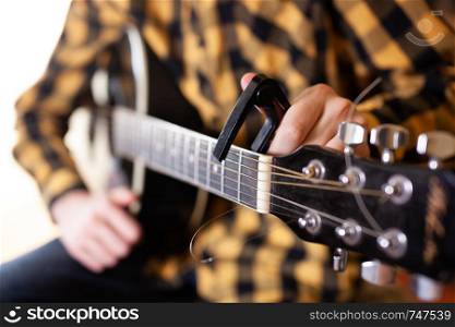 Instal a capodaster, also called capo, for guitar, put across the strings. Closeup