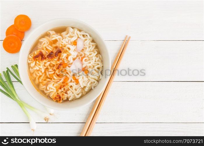 Instant noodles and vegetables on white wooden background, Top view of noodle and seasonings in cup on wood table