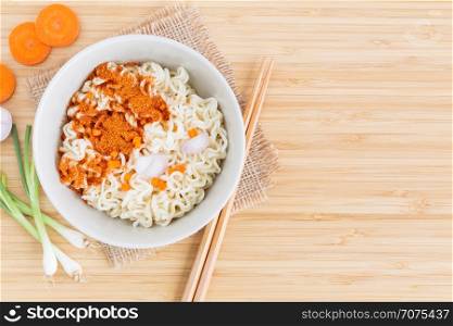 Instant noodles and vegetables on wooden background, Top view of noodle and seasonings in cup on bamboo wood table