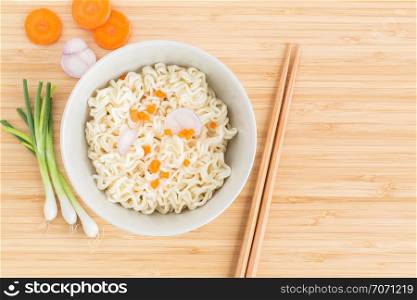 Instant noodles and vegetables on wooden background, Top view of noodle in cup on bamboo wood table