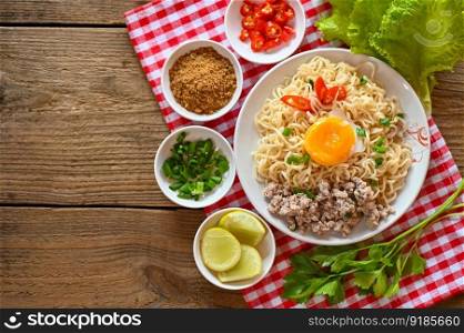 instant noodles cooking tasty eating with bowl - noodle soup, noodles bowl with boiled egg minced pork vegetable spring onion lemon lime lettuce celery and chili on table food 
