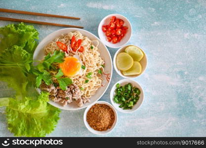 instant noodles cooking tasty eating with plate, noodles bowl with boiled egg minced pork vegetable spring onion lemon lime lettuce celery and chili on table food, noodle soup - top view