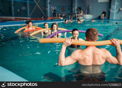 Instructor and female group on workout in swimming pool. Aqua aerobics training, water sport