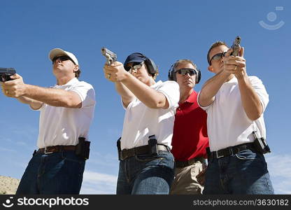 Instructor assisting people aiming guns at firing range