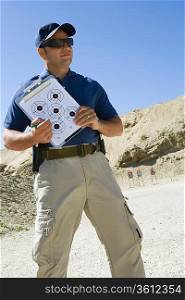 Instructor holding clipboard with target diagram at firing range