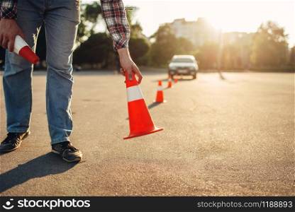 Instructor sets the cone for the examination, driving school concept. lesson for novice car drivers, test for beginner. Instructor sets the cone, driving school concept