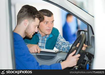 instructor teaching apprentice how to drive a factory vehicle
