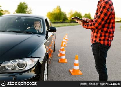 Instructor with checklist and woman in car, examination or lesson in driving school. Man teaching lady to drive vehicle, exam. Driver&rsquo;s license education. Instructor with checklist and woman in car, exam