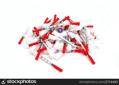 Insulin And Needles. Pile of used hypodermic syringes with half full vile of insulin in the middle