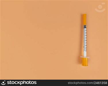 Insulin syringe on an orange background with copy space.. Insulin syringe on orange background with copy space.