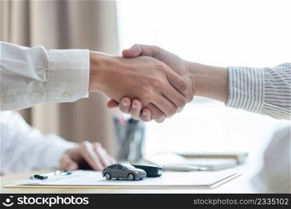 Insurance concept the car broker shaking hand with his customer after finishing dealing the contract.
