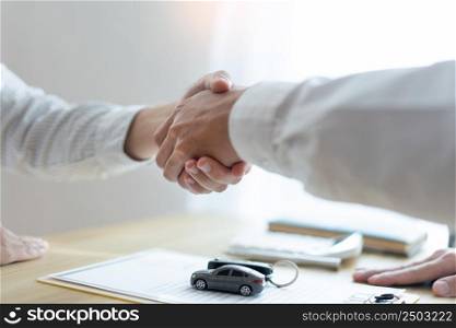 Insurance concept the car broker shaking hand with his customer after finishing dealing the contract.