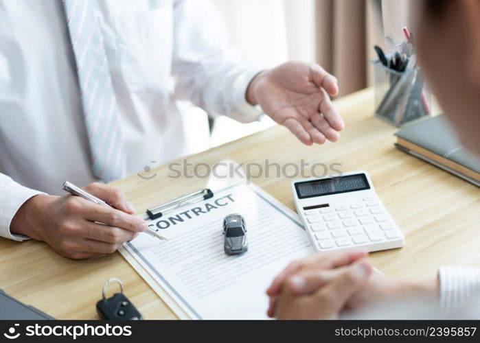 Insurance concept the car salesman describing the agreement on car contract to his customer.