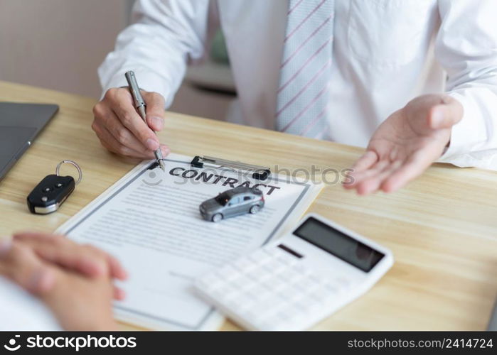 Insurance concept the car salesman describing the agreement on car contract to his customer.