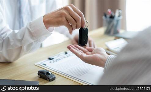 Insurance concept the customer receiving the car key after finishing the contract of car purchasing.