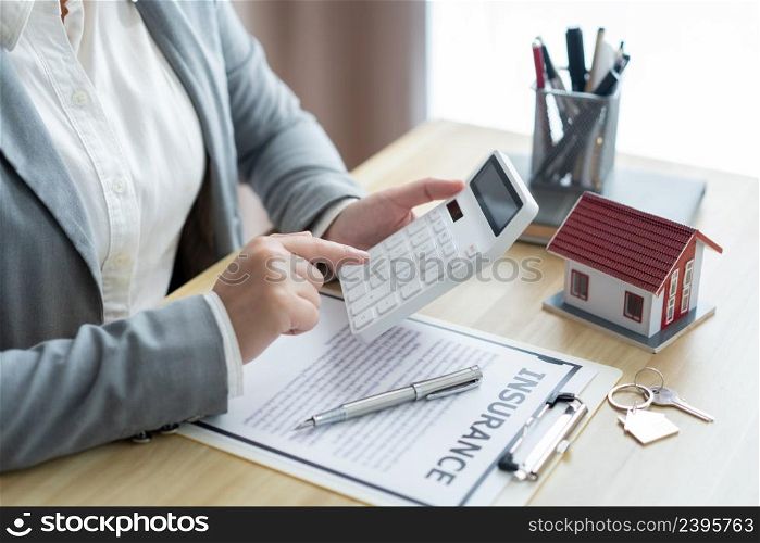 Insurance concept the estate broker pressing a calculator to calculate the price of the property.