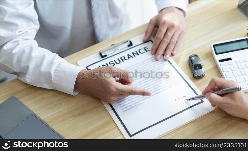 Insurance concept the male dealer suggesting his customer to sign the contract of car purchasing.
