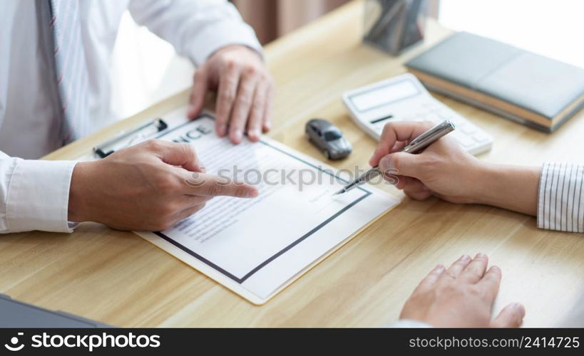 Insurance concept the male dealer suggesting his customer to sign the contract of car purchasing.