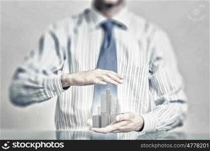 Insure your construction investments. Close up of hands holding image of modern cityscape