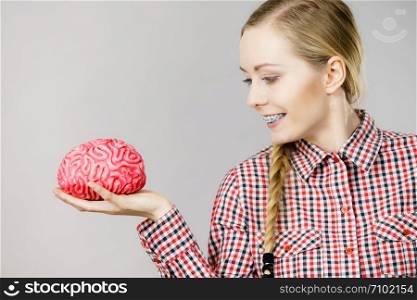 Intellectual expressions, being focused concept. Closeup of attractive woman happy thinking face expression holding brain. Woman thinking and holding fake brain