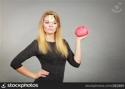 Intellectual expressions, being focused concept. Closeup of attractive woman thinking face expression holding brain having question mark on head. Woman thinking and holding fake brain