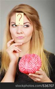 Intellectual expressions, being focused concept. Closeup of attractive woman thinking face expression holding brain having question mark on head. Woman thinking and holding fake brain